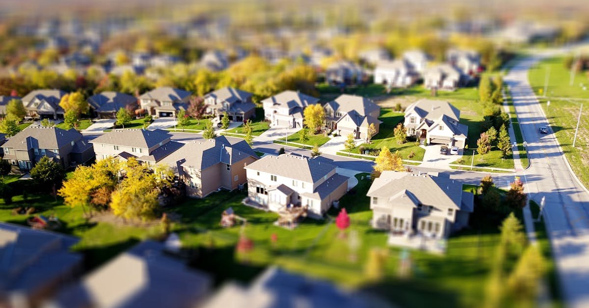 Tilt-shift aerial photo of a suburban neighborhood with green lawns and roads.